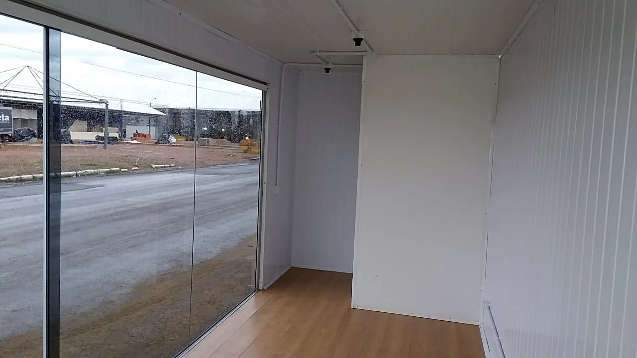 Interior de plantão de vendas com fachada de vidro e piso de madeira
